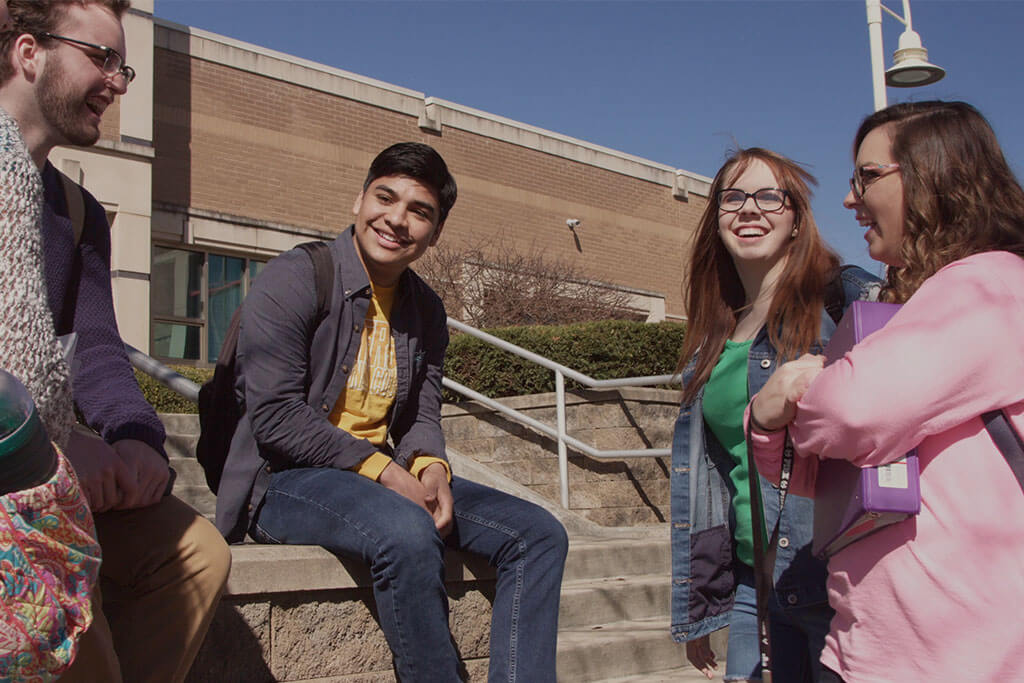 Group of four students gathered at table talking and laughing